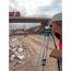 Person mit optischem Nivelliergerät auf Baustelle