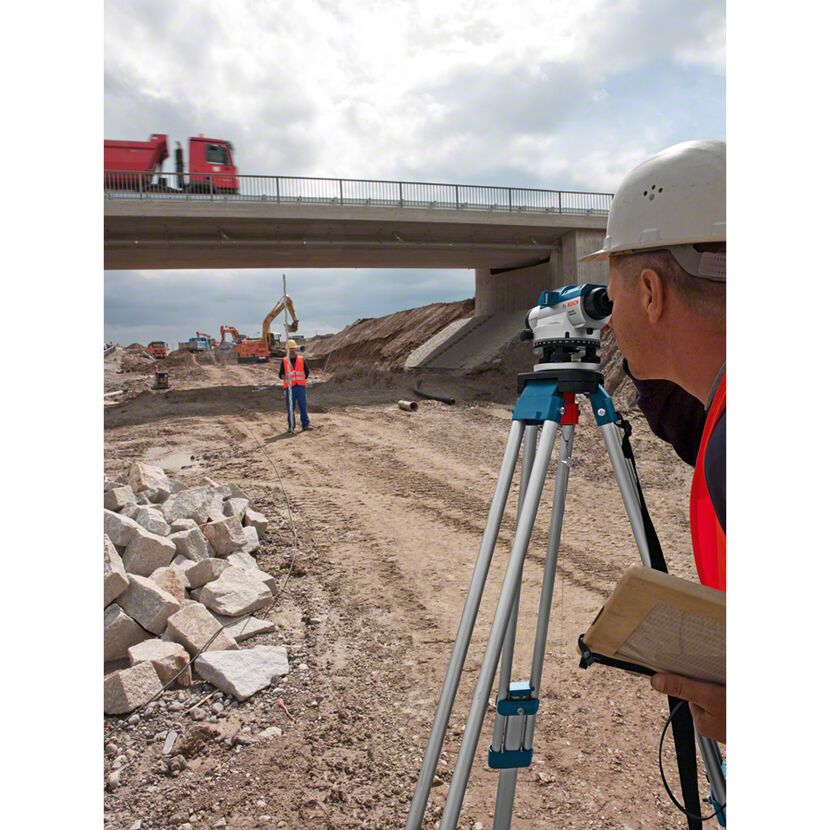 Person mit Nivelliergerät auf Baustelle