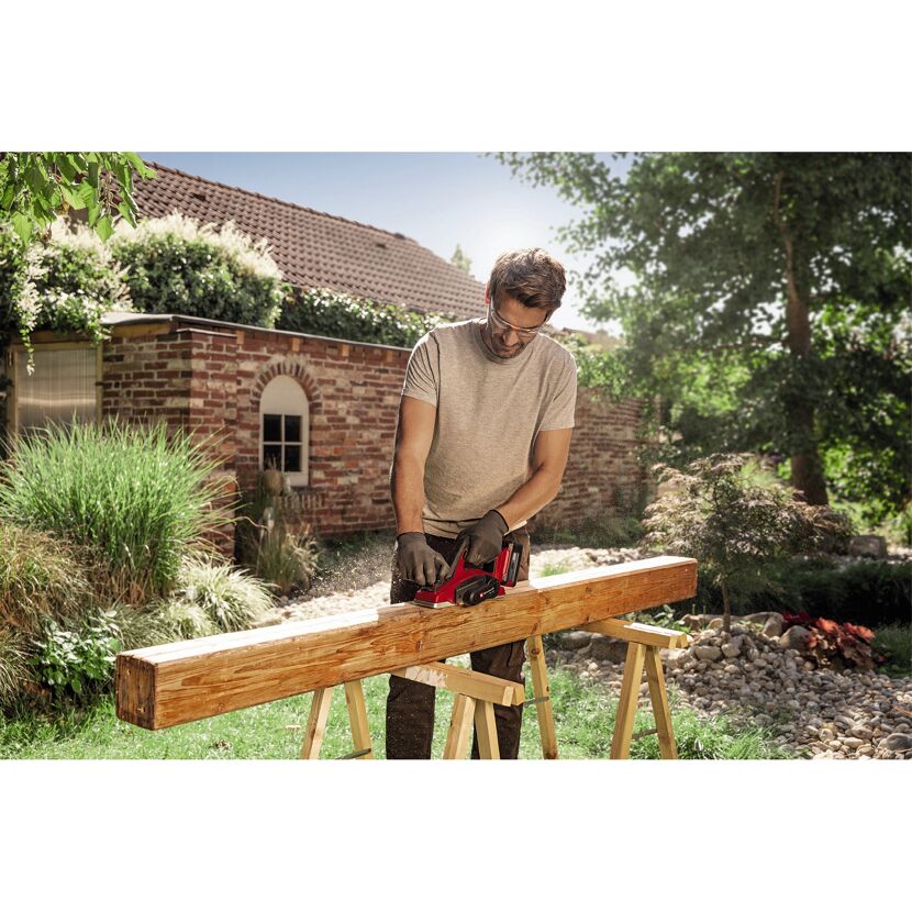 Person hobelt Holzbalken mit Akku-Hobel