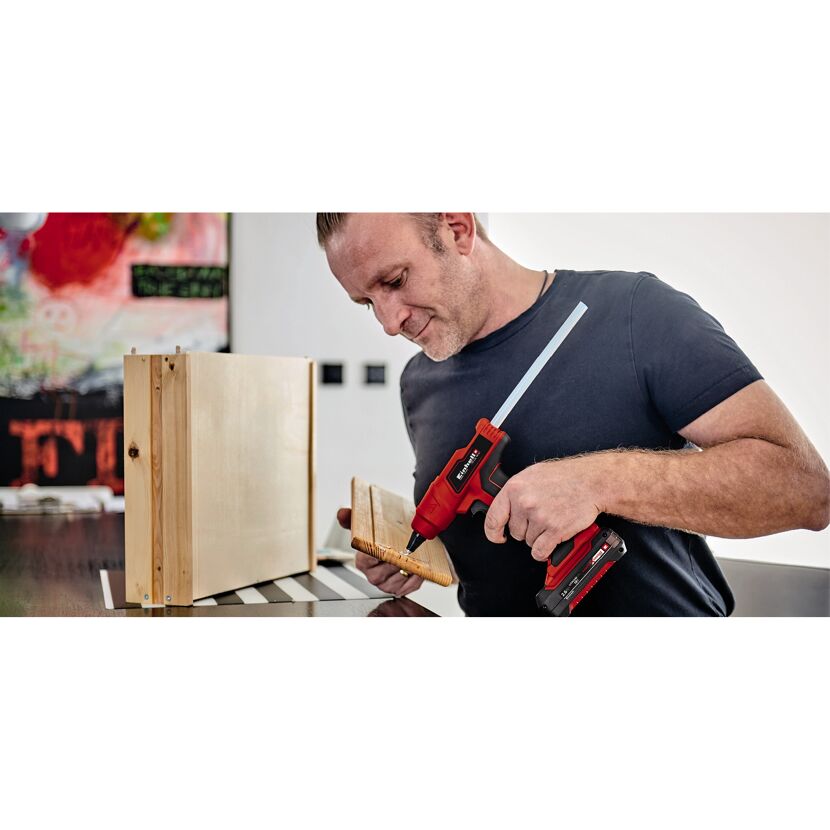 Person klebt Holz mit Akku-Heißklebepistole