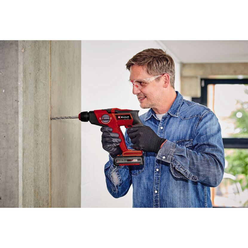 Person bohrt mit Akku-Bohrhammer in Betonwand