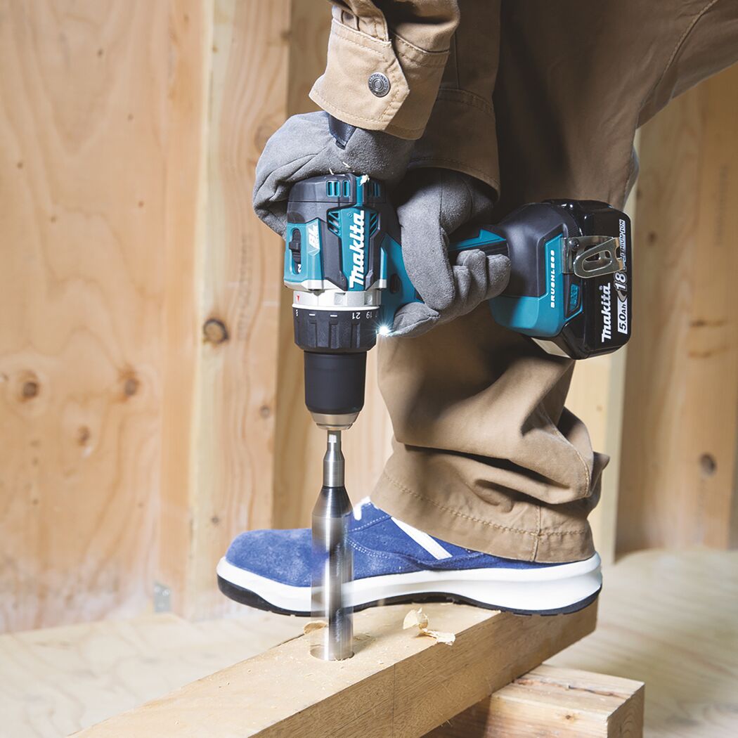 Person bohrt mit einem Makita Akku-Bohrschrauber in ein Holzstück.