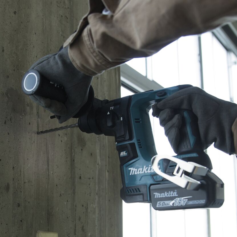 Person bohrt mit Akku-Bohrhammer in Betonwand