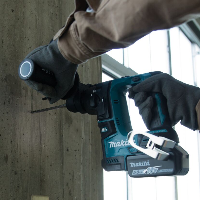 Person bohrt mit einem Akku-Bohrhammer in eine Betonwand.