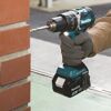 Person bohrt mit Makita Akku-Schlagbohrschrauber in eine Ziegelwand