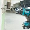 Person bohrt mit einem Makita Akku-Kombihammer in eine Wand.