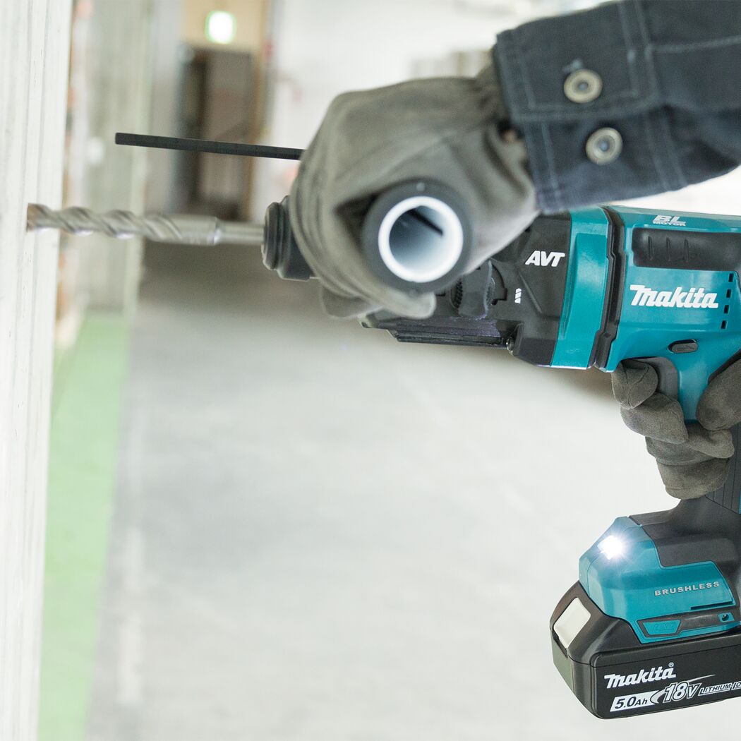 Person bohrt mit einem Makita Akku-Kombihammer in eine Wand.