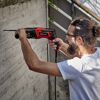 Person bohrt mit Bohrhammer in Betonwand.