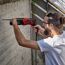 Person bohrt mit Bohrhammer in Betonwand.