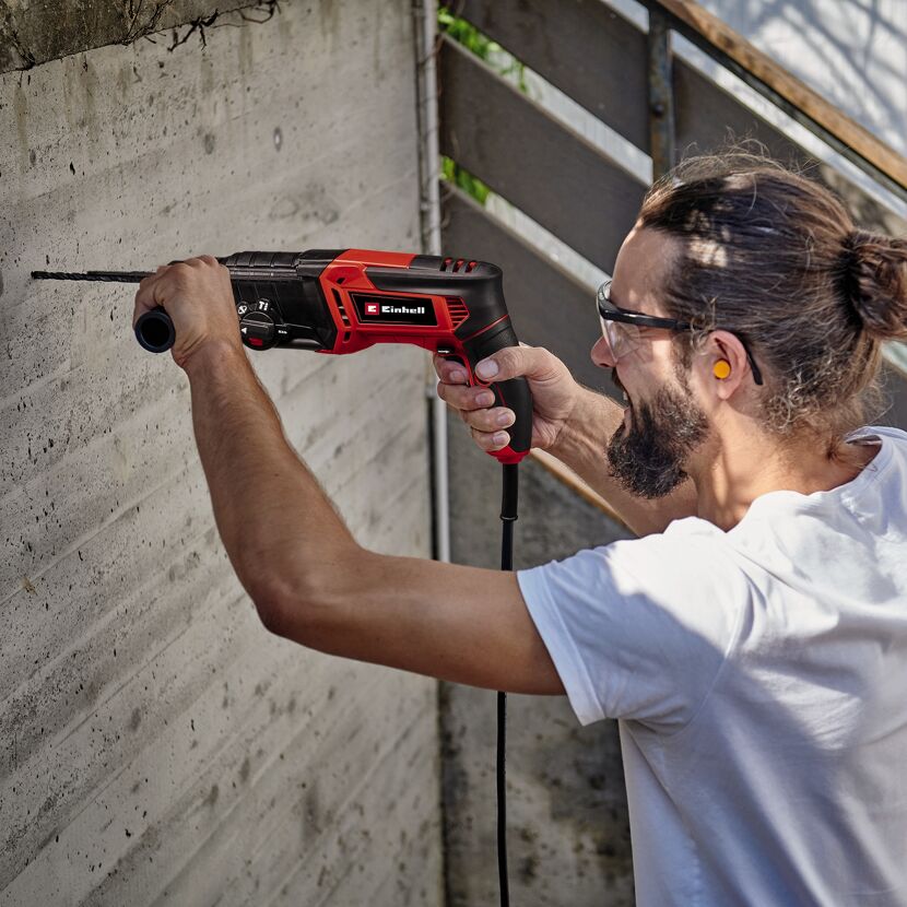 Person bohrt mit Bohrhammer in Betonwand.