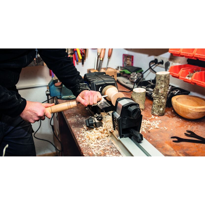 Person drechselt Holz mit Drechselbank und Drechseleisen