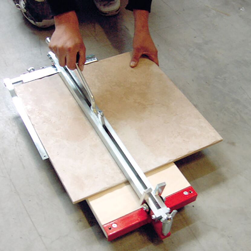 Person schneidet Fliese mit Fliesenschneider