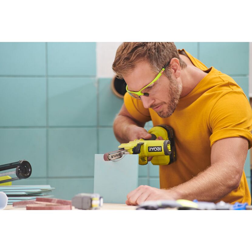 Person schleift mit RYOBI Akku-Bandfeile eine Fliese