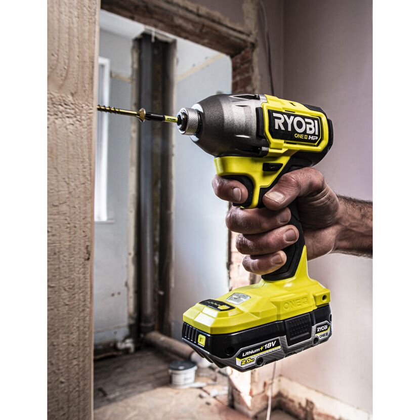 Hand hält einen Ryobi Akku-Schlagschrauber und schraubt eine Schraube in ein Holzbrett.