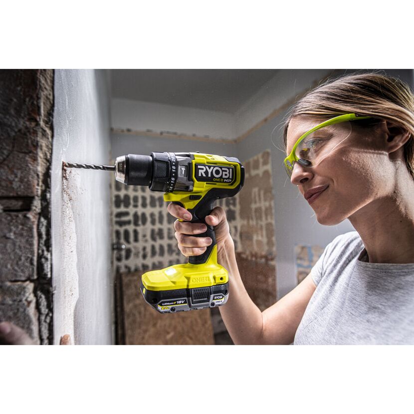 Person bohrt mit einem RYOBI Akku-Schlagbohrschrauber in eine Wand.