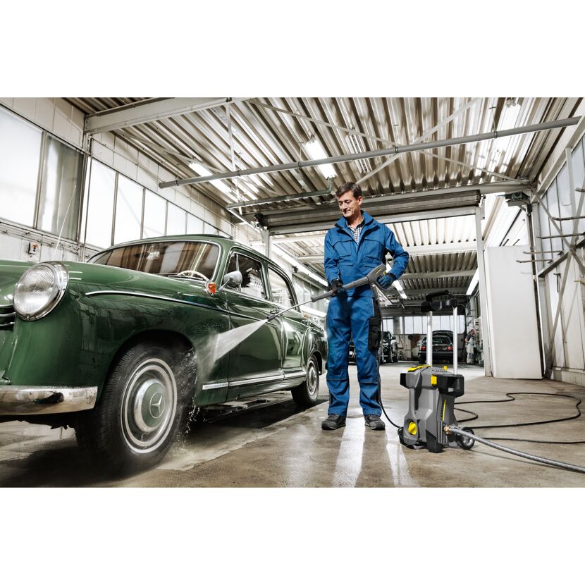 Person reinigt einen Oldtimer mit einem Hochdruckreiniger.