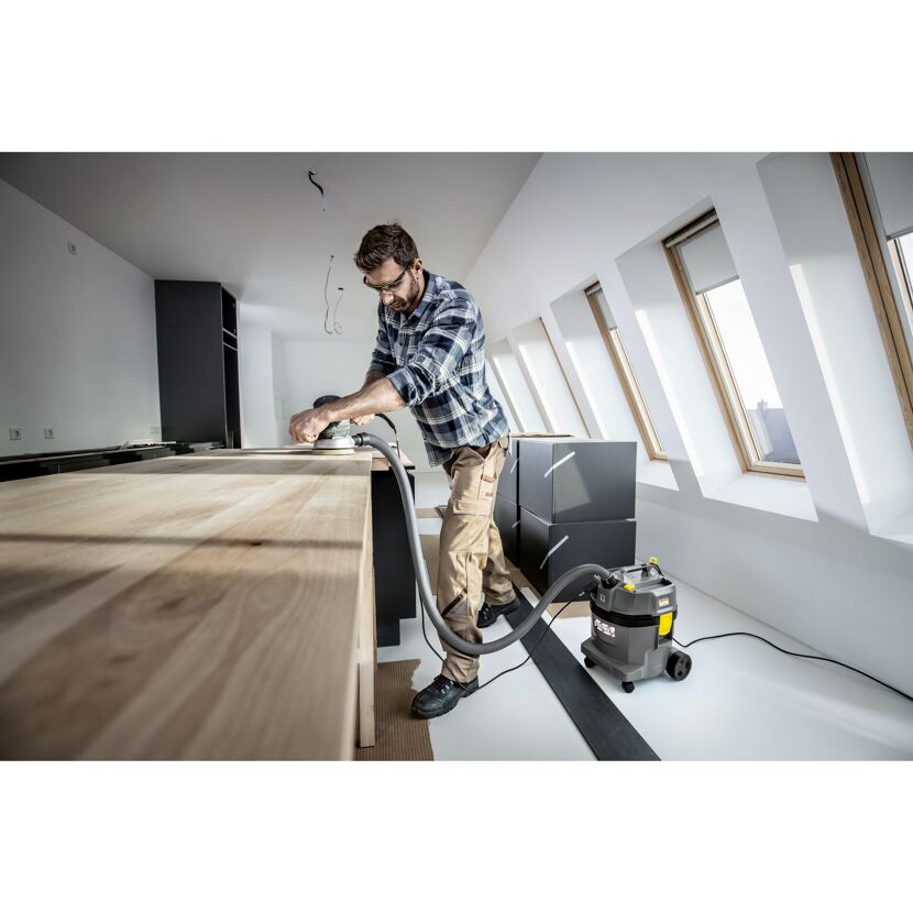 Person schleift eine Holzplatte mit einem Schwingschleifer ab.
