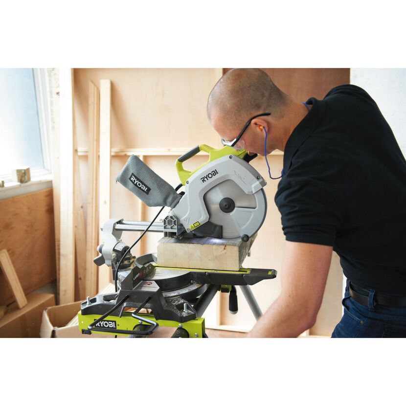 Person sägt mit einer Ryobi Kapp- und Gehrungssäge ein Stück Holz.