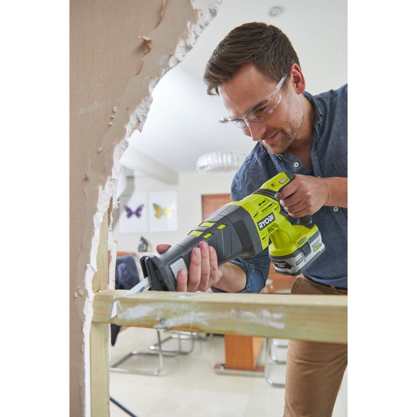 Person sägt mit einer Akku-Säbelsäge von Ryobi in ein Holzbrett.