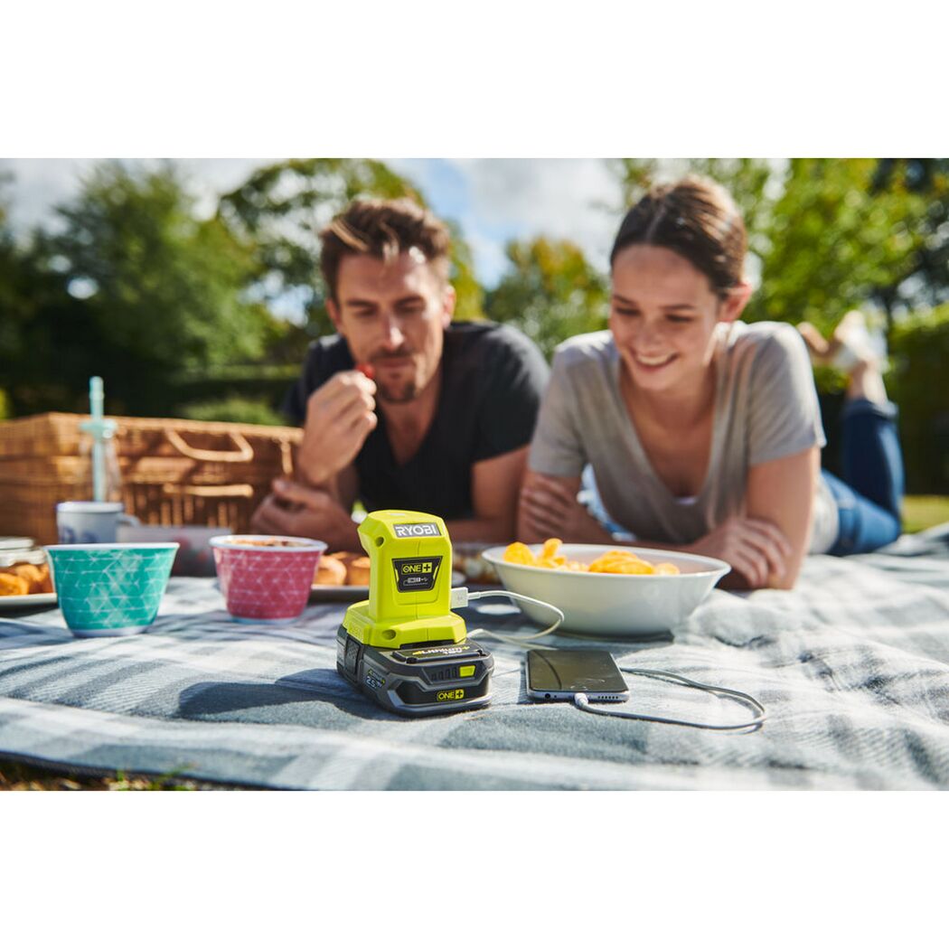 RYOBI Akku-USB-Adapter lädt Smartphone beim Picknick.