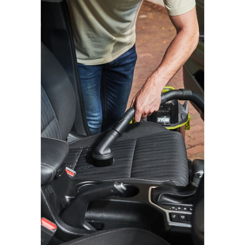 Person saugt Autositz mit RYOBI Akkusauger.