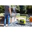 Person grillt im Garten, daneben steht eine Akku Bluetooth Box von Ryobi.