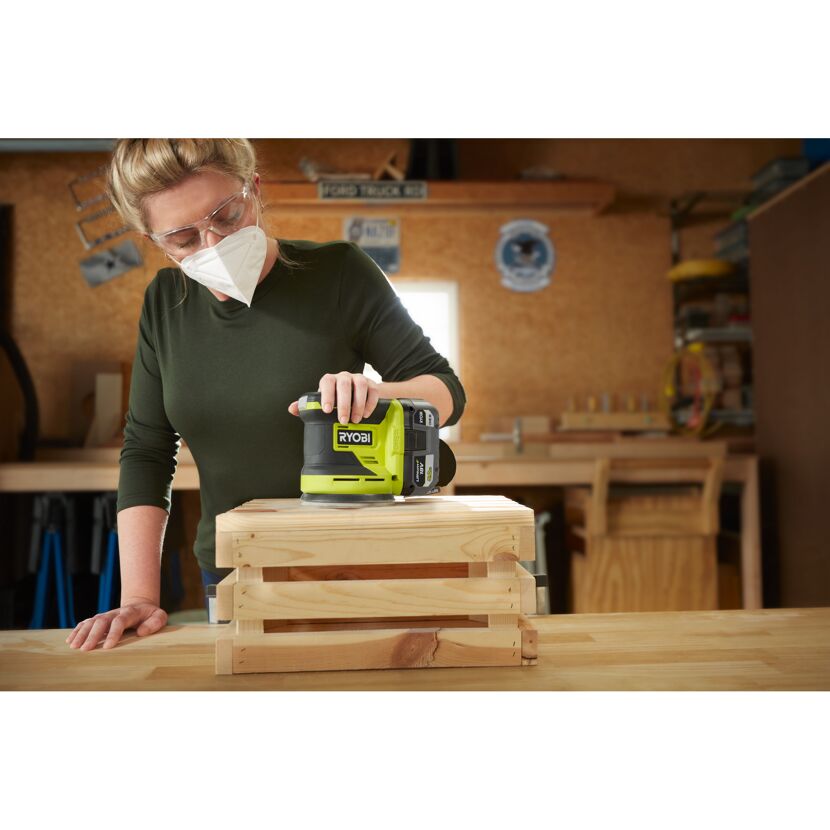 Person schleift Holz mit RYOBI Exzenterschleifer