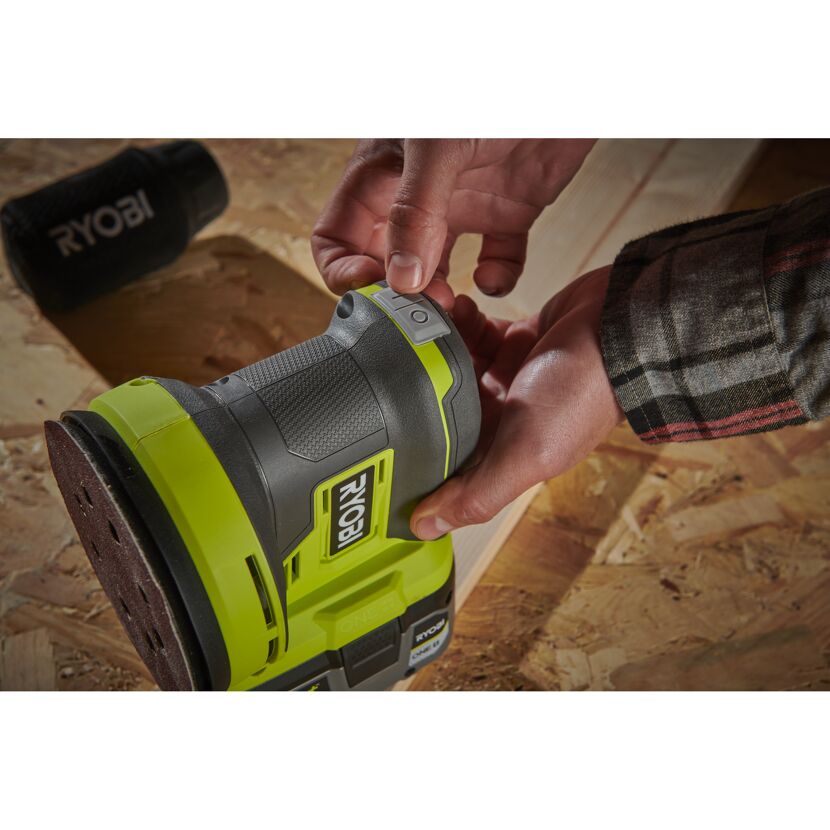 Person schaltet einen Ryobi Exzenterschleifer ein.