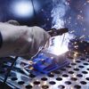 Person schweißt Metall mit Schutzhandschuhen