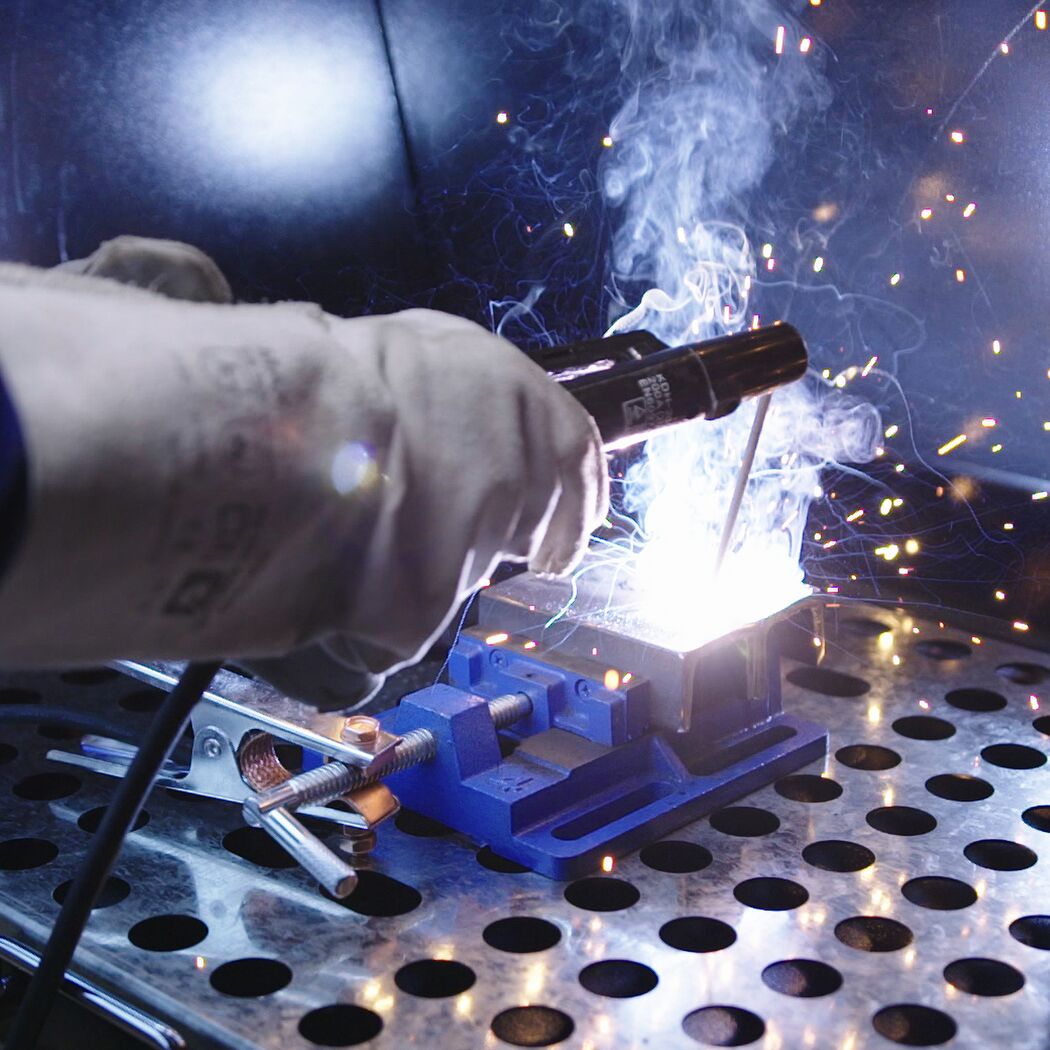 Person schweißt Metall mit Schutzhandschuhen