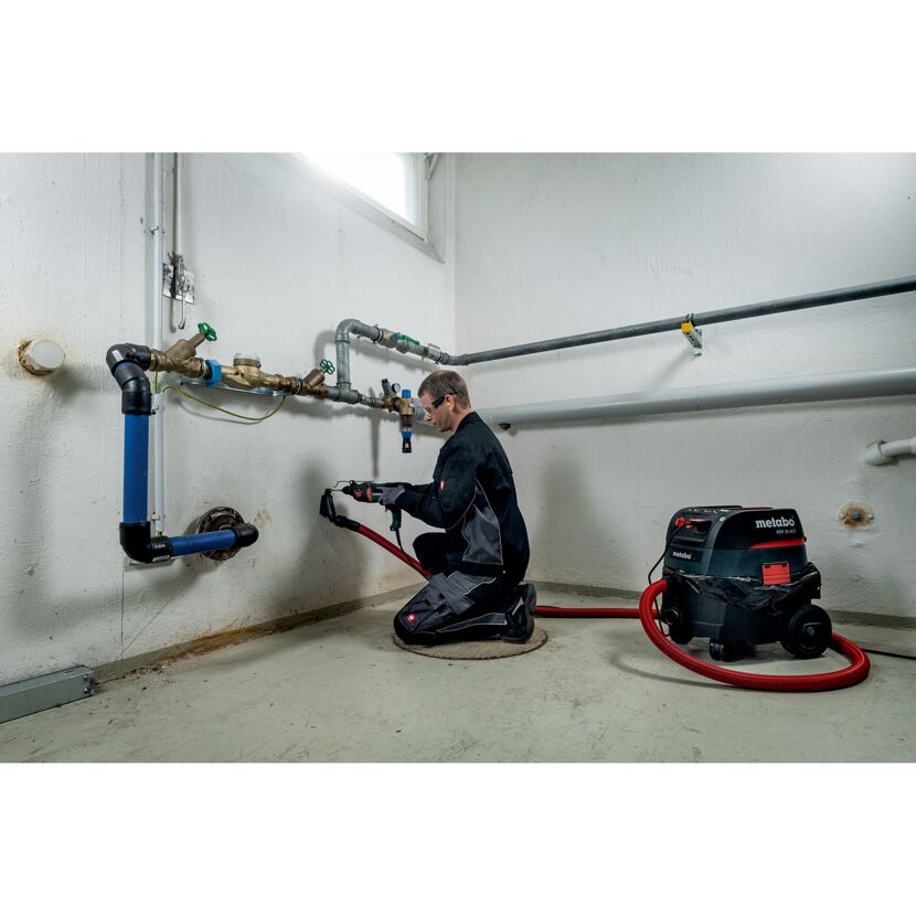 Person bohrt mit Kombihammer ein Loch in die Wand.