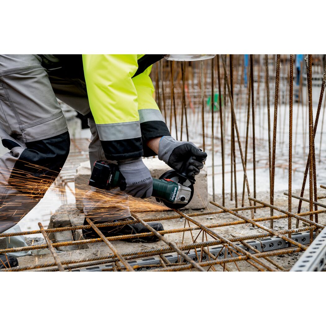 Person verwendet einen Winkelschleifer zum Schneiden von Metallstreben.