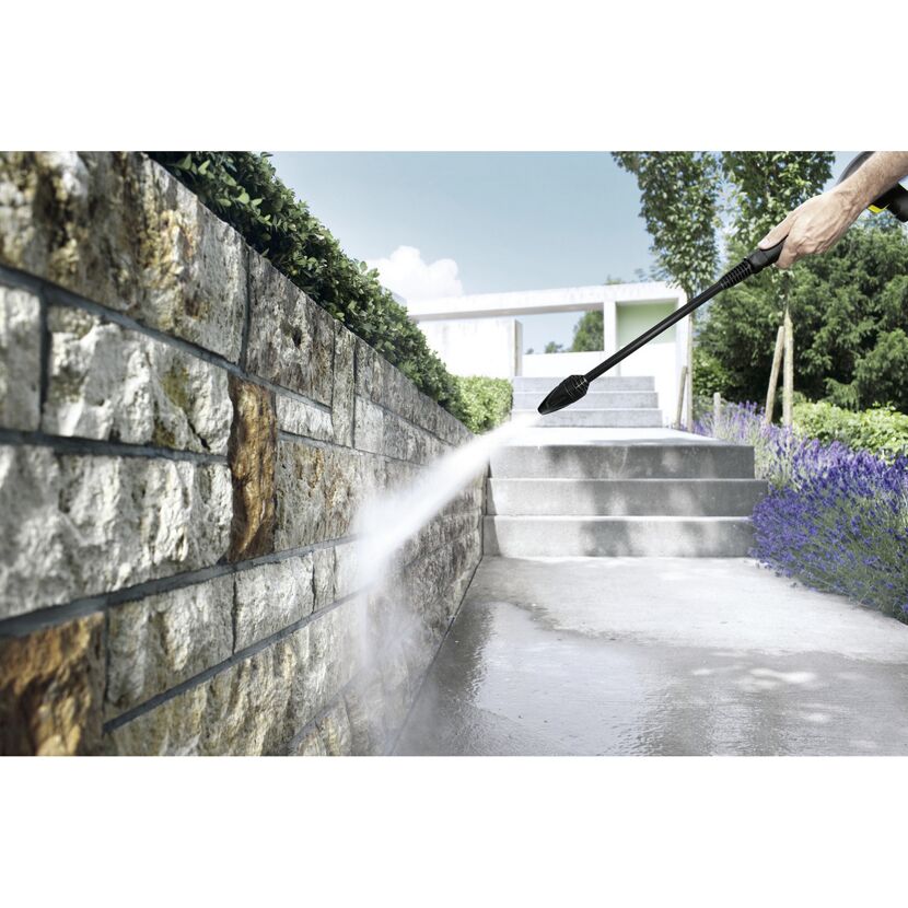Person reinigt eine Steinmauer mit einem Hochdruckreiniger.