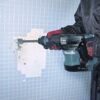 Person entfernt Fliesen mit dem Makita Meißelhammer.