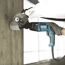 Person bohrt mit Makita Bohrhammer in Betonwand.
