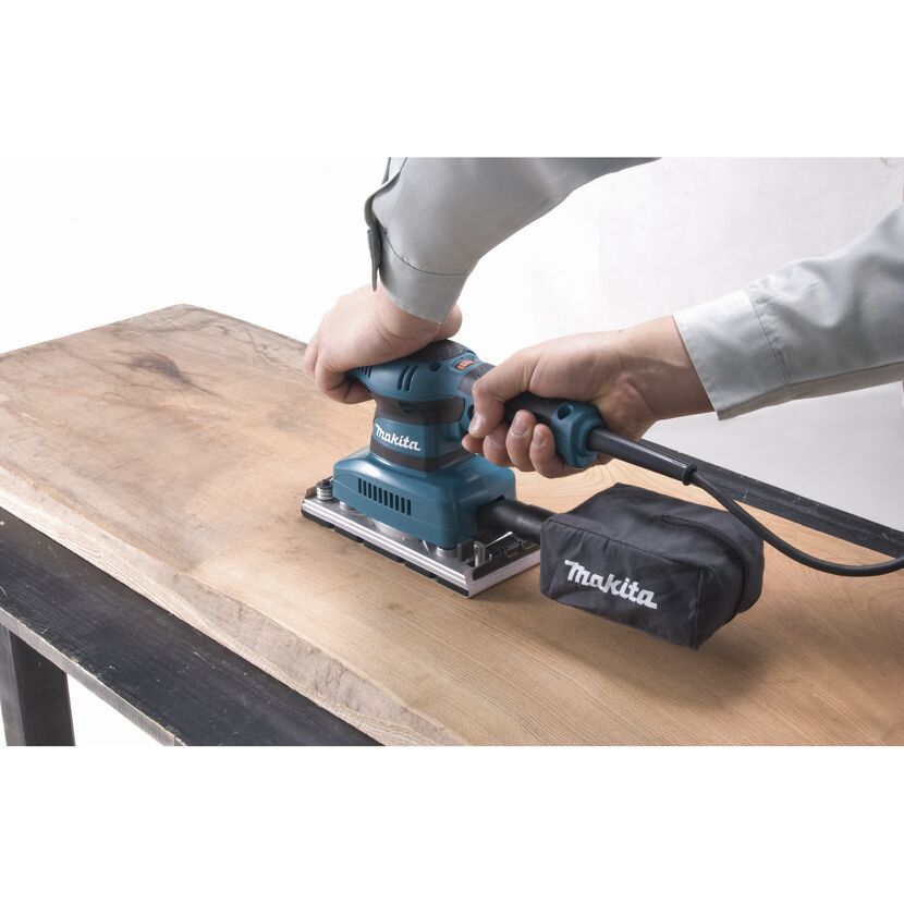 Person schleift Holz mit Makita-Schwingschleifer