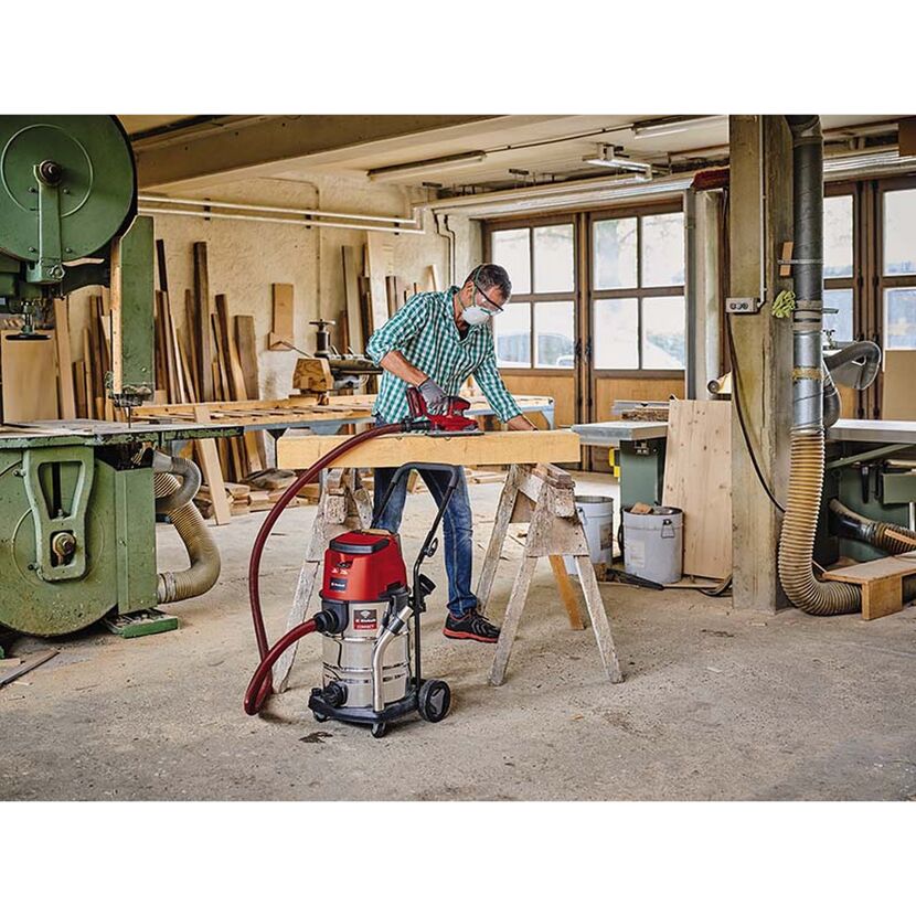 Person schleift Holz mit Schleifmaschine und Industriestaubsauger