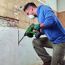 Person entfernt Fliesen mit Bohrhammer.
