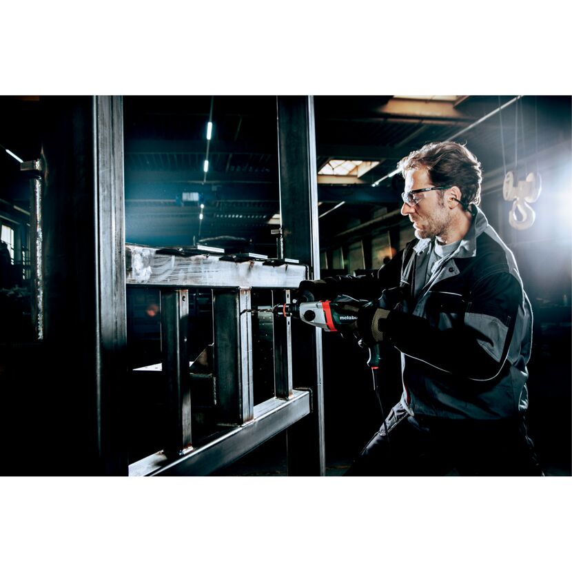 Person bohrt mit einer Schlagbohrmaschine in Metallträger.