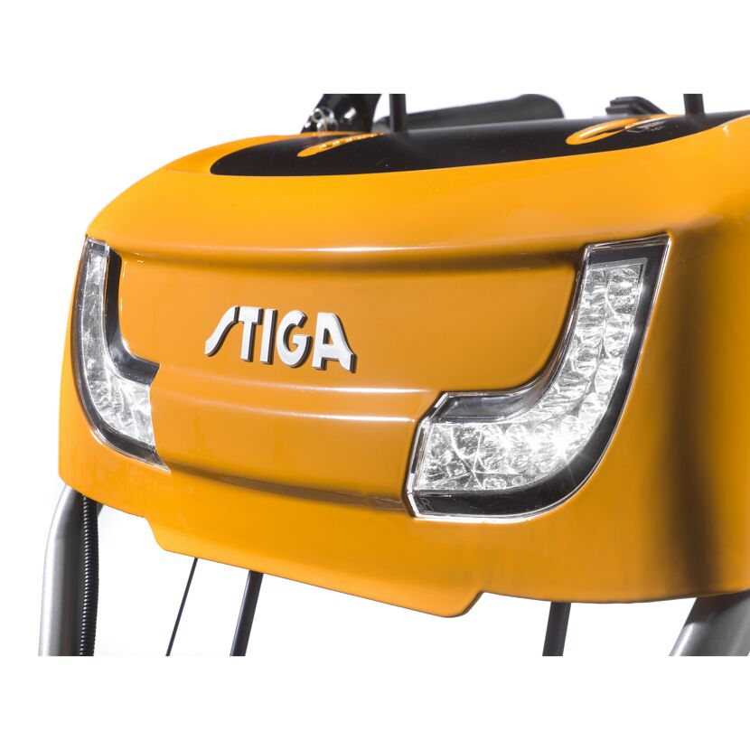 Vorderseite der orangenen Kehrmaschine SWS 800 GE mit eingeschalteten Scheinwerfern