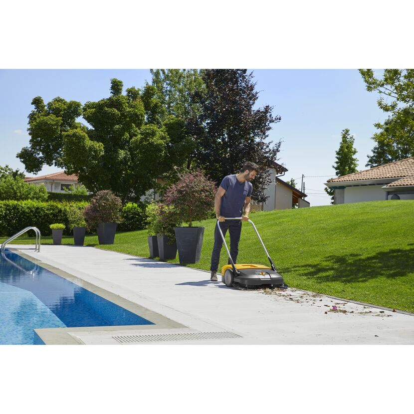 Person kehrt mit Kehrmaschine am Pool