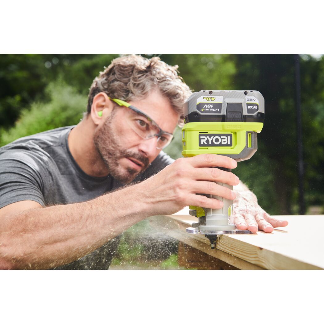 Person fräst mit einer Akku-Kantenfräse von Ryobi Holz.