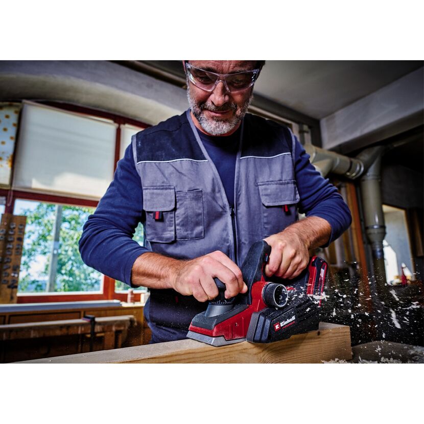 Person hobelt Holz mit Akku Hobel