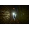 Person mit Taschenlampe in Holztunnel