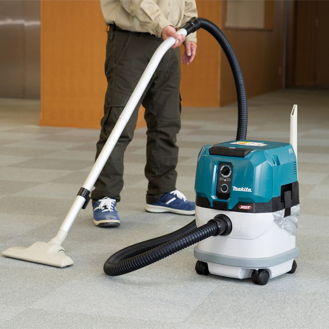 Person saugt Teppich mit Makita Staubsauger