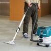 Person saugt Teppich mit Makita-Staubsauger