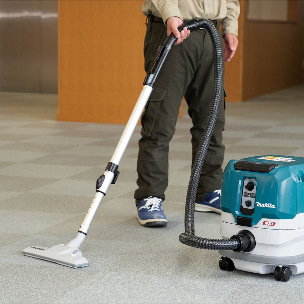 Person saugt Teppich mit Makita-Staubsauger