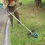 Person trimmt Rasen mit Freischneider