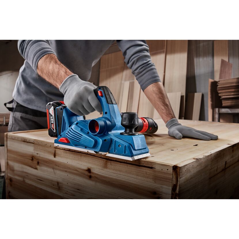 Person bearbeitet Holz mit Elektrohobel
