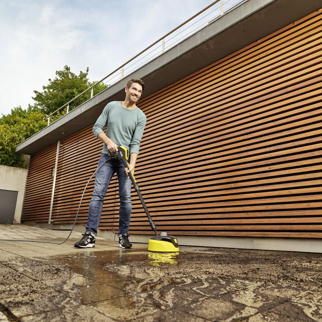 Person reinigt Terrasse mit Hochdruckreiniger